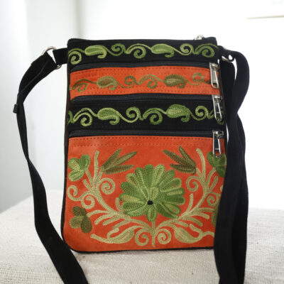 Oranje: Suede Fairtrade schoudertas oranje met groen borduur, drie ritsvakken – De Loohof